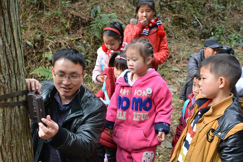 Fanjingshan nature reserve biologist Lei Shi showed children how to mount a camera trap on a tree. (Photo by Kefeng Niu)