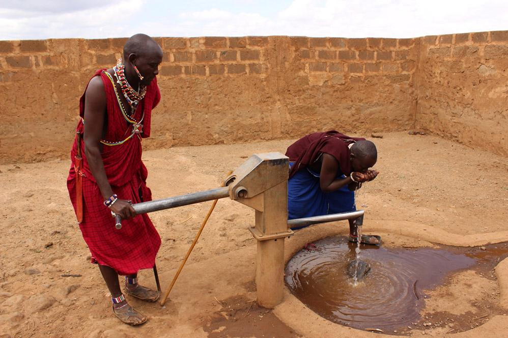 Two Maasai warriors get some refreshment by the new water pump near their boma just outside Ambsolei National Park, surrounded by a wall to protect against elephant damage.